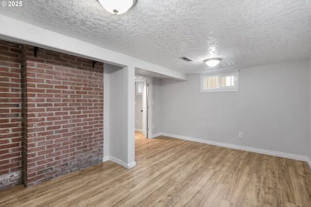 basement featuring a textured ceiling and light hardwood / wood-style flooring