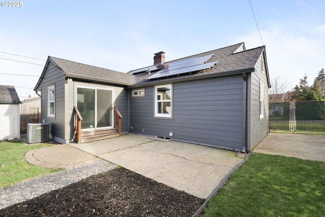 rear view of property featuring solar panels, an outdoor structure, and a lawn