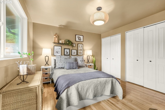 bedroom featuring multiple closets and light wood-style flooring
