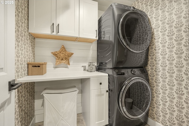 laundry room featuring stacked washer and clothes dryer and cabinet space