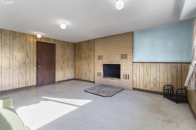 unfurnished living room featuring a textured ceiling, a fireplace, and wood walls