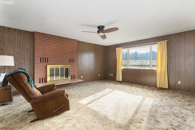 carpeted living room featuring ceiling fan, a fireplace, and wooden walls