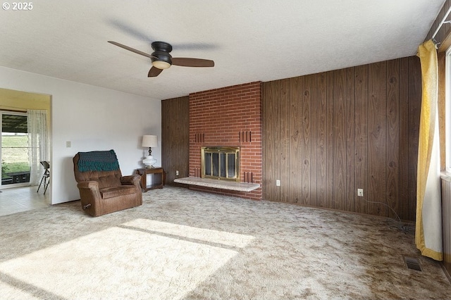 living room with a brick fireplace, carpet floors, a textured ceiling, and wooden walls