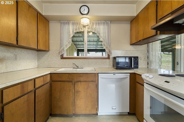 kitchen featuring sink, white appliances, and backsplash