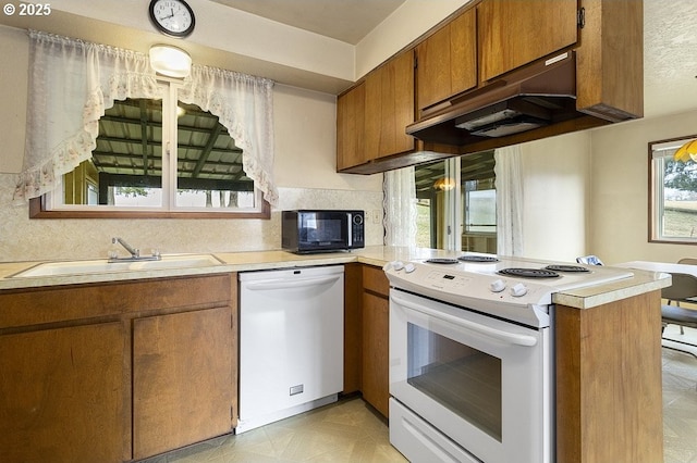 kitchen with sink, backsplash, white appliances, and kitchen peninsula