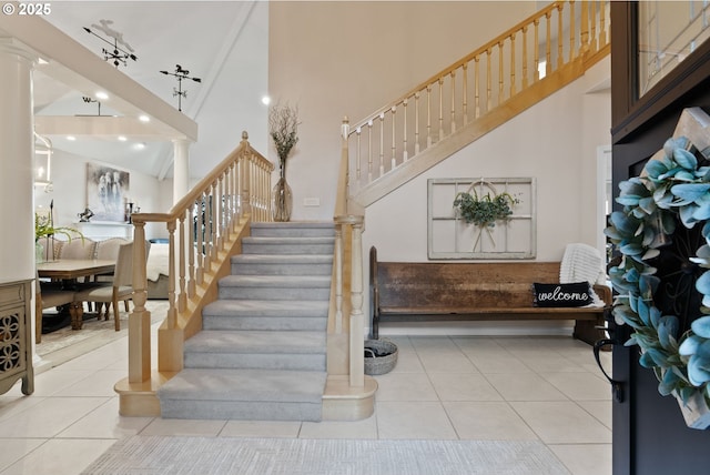 stairway featuring decorative columns, track lighting, high vaulted ceiling, and tile patterned flooring