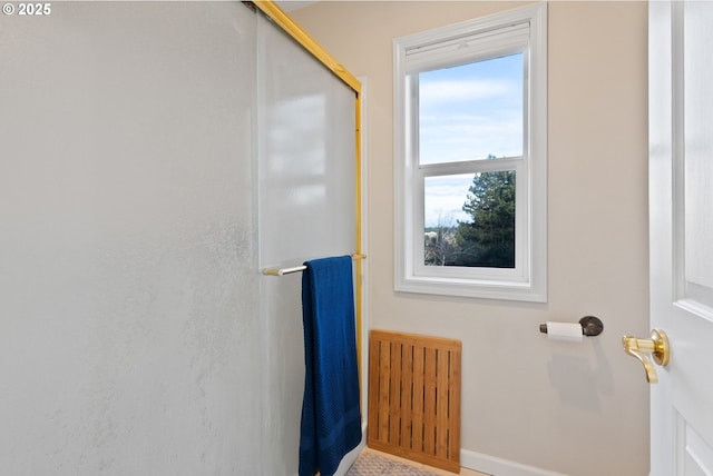 bathroom featuring radiator, a shower with door, and baseboards