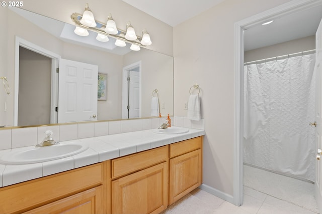 full bath with double vanity, tile patterned flooring, a sink, and baseboards