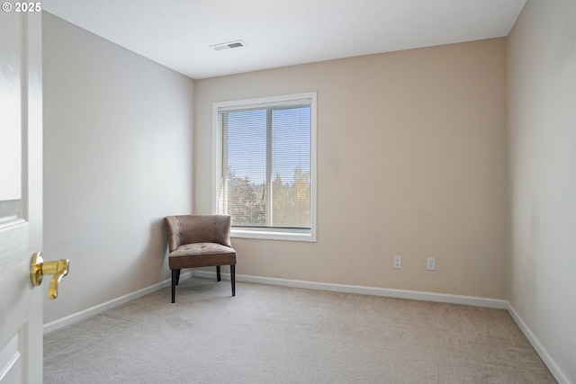 sitting room with light colored carpet, visible vents, and baseboards