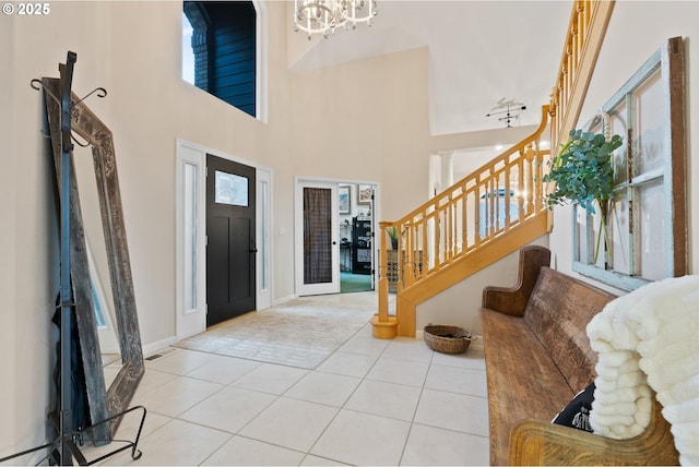 entryway with light tile patterned floors, a notable chandelier, visible vents, a towering ceiling, and stairs