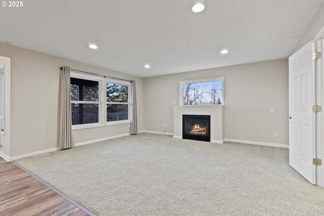 unfurnished living room featuring baseboards, a glass covered fireplace, and recessed lighting