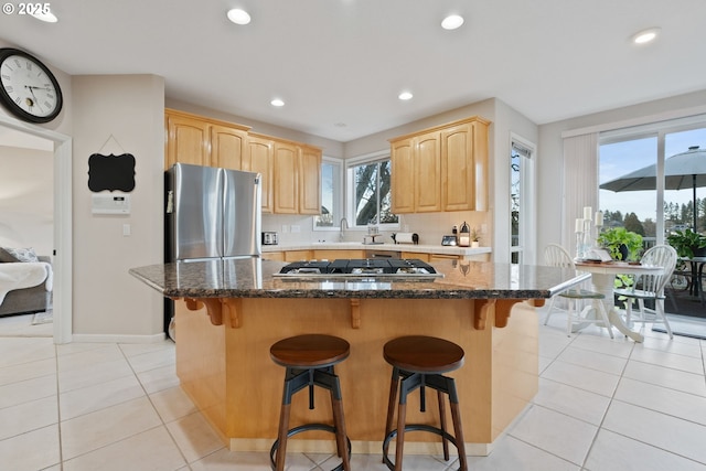 kitchen with light tile patterned floors, tasteful backsplash, appliances with stainless steel finishes, and light brown cabinetry