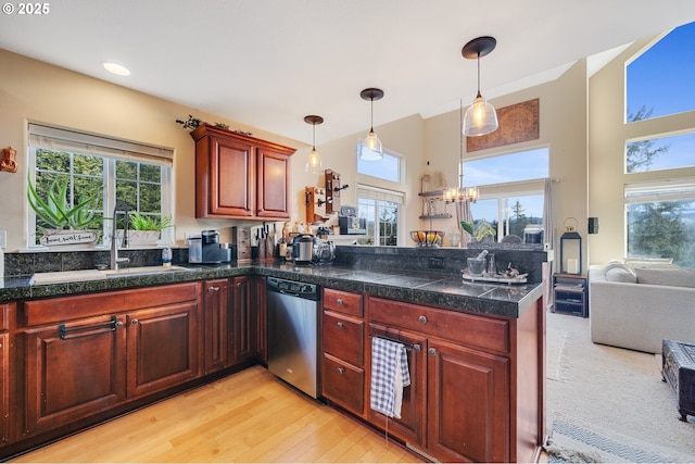 kitchen with decorative light fixtures, a wealth of natural light, stainless steel dishwasher, and light wood-type flooring