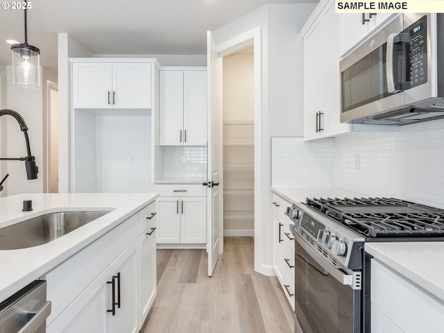 846 NW 178th Way, Ridgefield, WA 98642 - kitchen with appliances with stainless steel finishes, light wood-type flooring, white cabinetry, tasteful backsplash, and light countertops