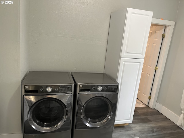 clothes washing area with cabinets, dark hardwood / wood-style floors, and washer and dryer