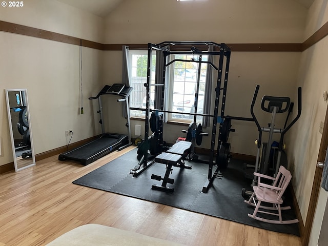 exercise area with light hardwood / wood-style floors and vaulted ceiling