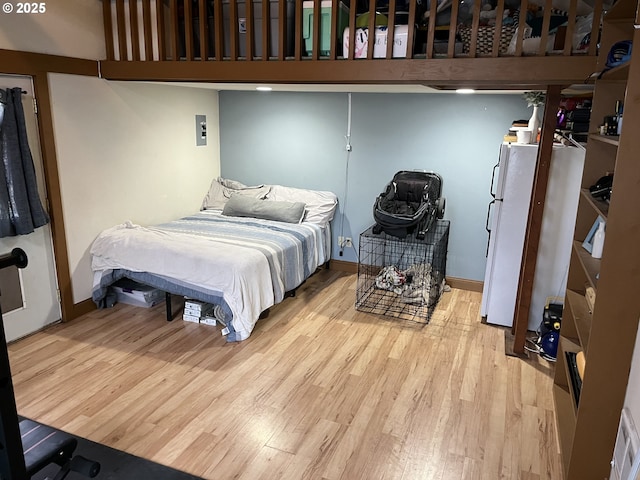 bedroom featuring white refrigerator and light hardwood / wood-style flooring