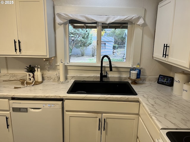 kitchen featuring white cabinets, white dishwasher, light stone counters, and sink