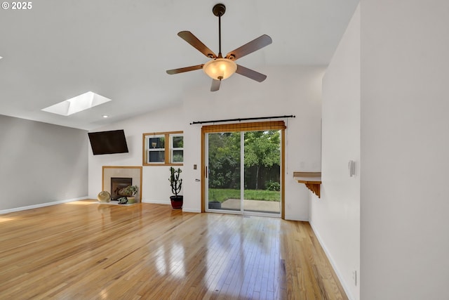 668 River Rd, Eugene, OR 97404 - unfurnished living room with a skylight, a tiled fireplace, hardwood / wood-style floors, a ceiling fan, and high vaulted ceiling