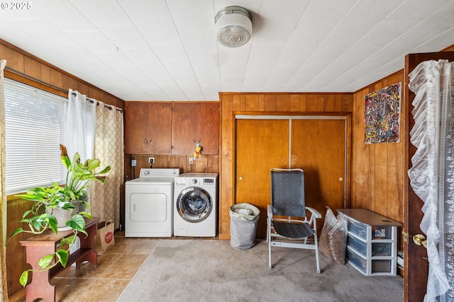 laundry room featuring cabinets, washing machine and clothes dryer, wooden walls, and light carpet