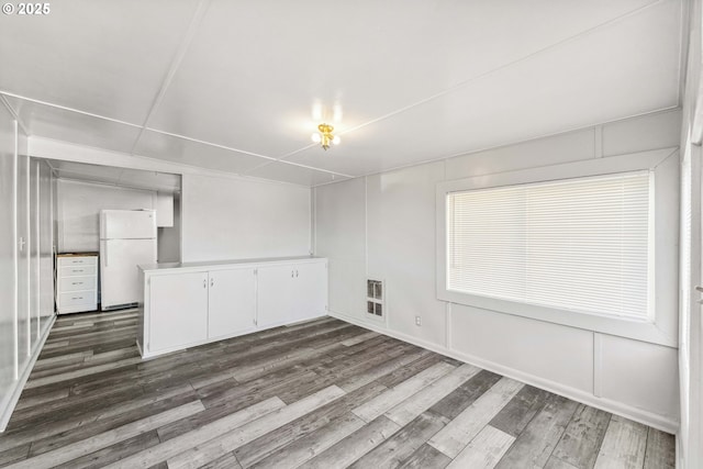 empty room with dark wood-type flooring and heating unit