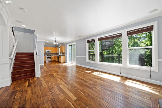 3541 SW Wonderview Ave, Gresham, OR 97080 - unfurnished living room featuring ornamental molding, a chandelier, wood finished floors, stairs, and baseboards