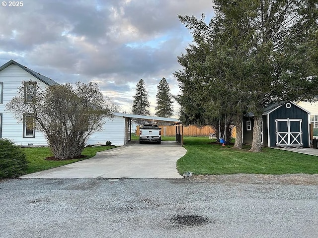 view of front of home with a carport, an outdoor structure, a storage unit, concrete driveway, and a front lawn