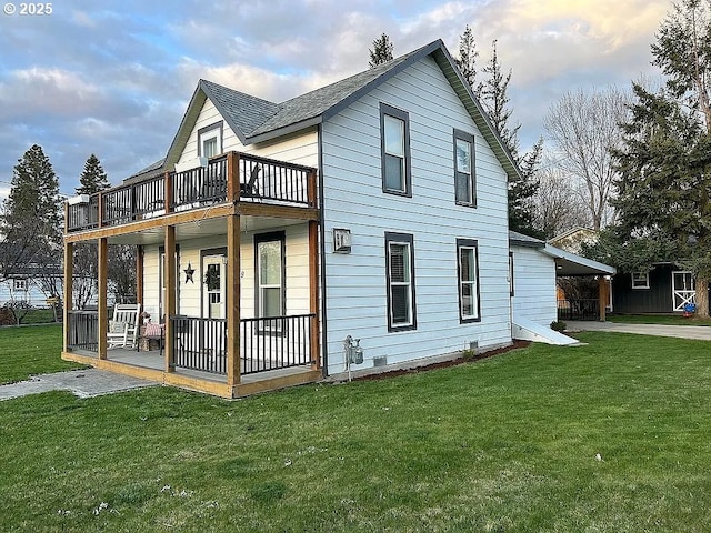 rear view of house featuring covered porch, a yard, a shingled roof, and a balcony