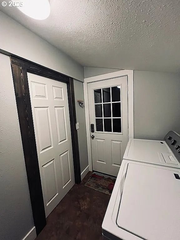 clothes washing area with washing machine and clothes dryer, a textured ceiling, and laundry area