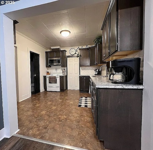 kitchen with a sink, light countertops, stainless steel microwave, baseboards, and white electric stove