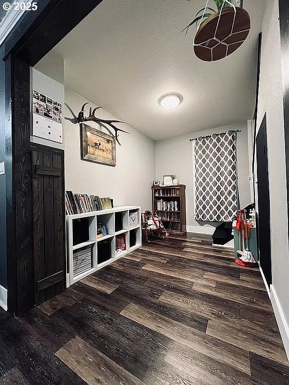 game room featuring baseboards, a textured ceiling, and wood finished floors