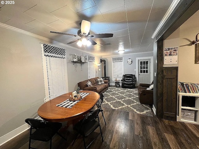 dining space with crown molding, dark wood finished floors, a ceiling fan, baseboards, and visible vents