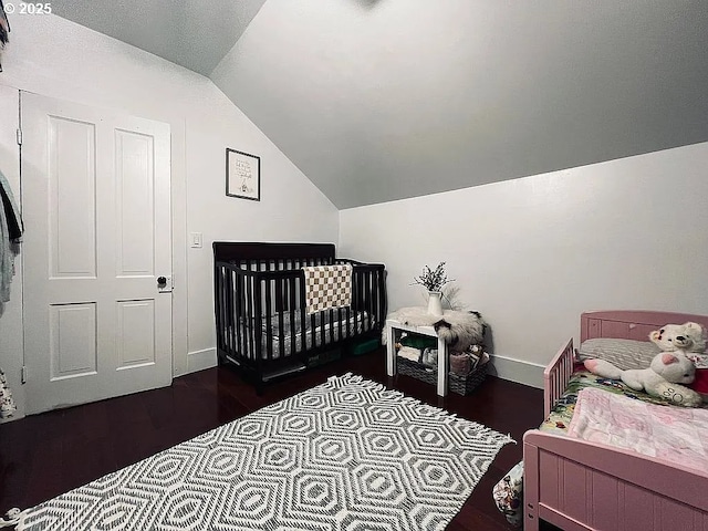bedroom with dark wood-style flooring, baseboards, and vaulted ceiling