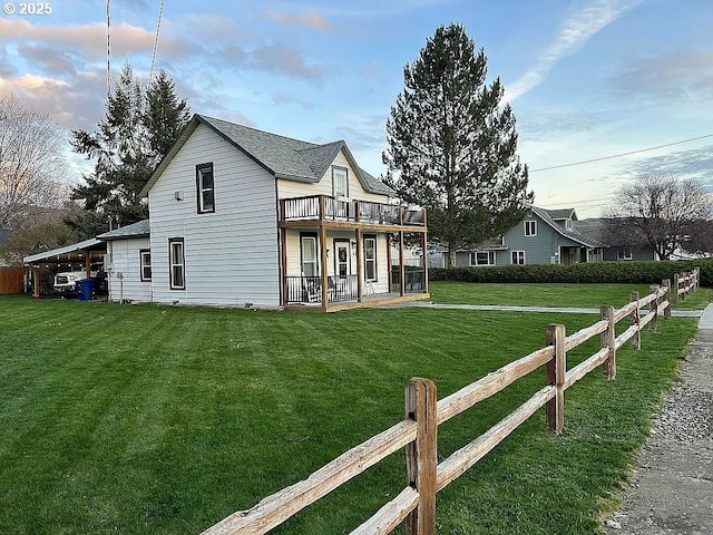 back of property with a lawn, roof with shingles, fence, and a deck