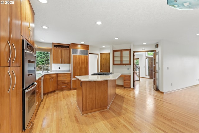 1324 Stonehaven Dr, West Linn, OR 97068 - kitchen with brown cabinetry, appliances with stainless steel finishes, light wood-style floors, a kitchen island, and light countertops