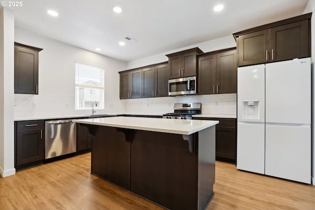 kitchen featuring a kitchen breakfast bar, a kitchen island, light hardwood / wood-style floors, and stainless steel appliances