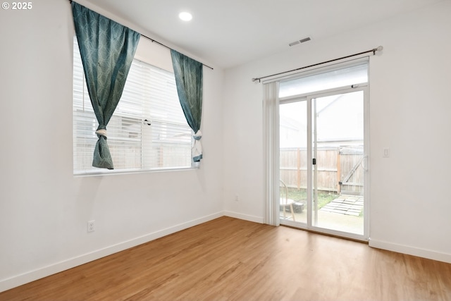 empty room with hardwood / wood-style floors and plenty of natural light