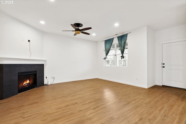 unfurnished living room featuring ceiling fan, light hardwood / wood-style flooring, and a fireplace