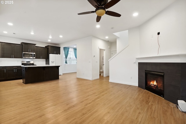 interior space with a fireplace, ceiling fan, and light wood-type flooring