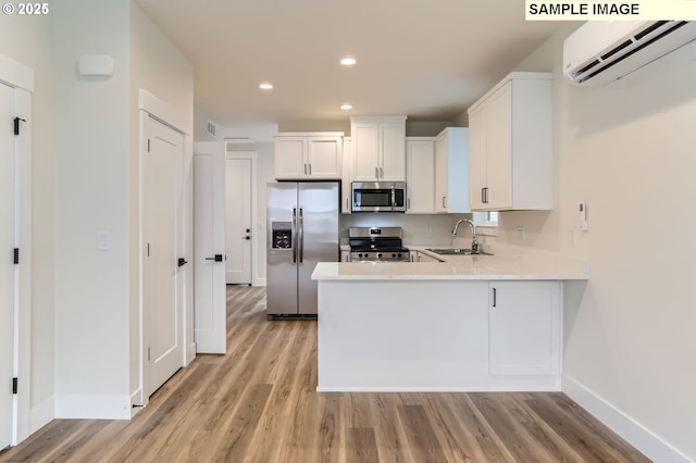 7762 SW Bonita Blvd, Tigard, OR 97224 - kitchen featuring appliances with stainless steel finishes, a wall unit AC, a sink, baseboards, and light wood-type flooring