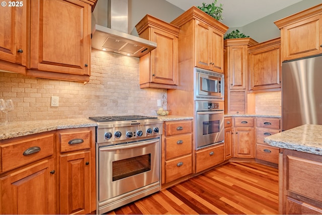 21106 NW 3rd Ct, Ridgefield, WA 98642 - kitchen with stainless steel appliances, wall chimney exhaust hood, light wood-style floors, light stone countertops, and backsplash
