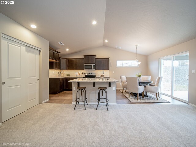 885 Yoss Pl, Cottage Grove, OR 97424 - kitchen with appliances with stainless steel finishes, light colored carpet, vaulted ceiling, dark brown cabinets, and a kitchen breakfast bar