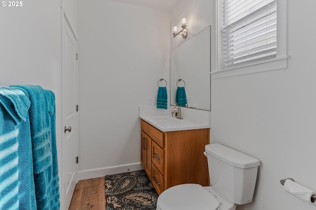 bathroom featuring baseboards, vanity, toilet, and wood finished floors