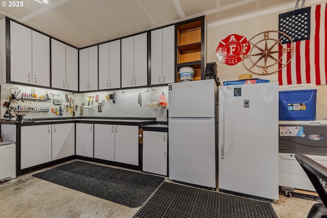 kitchen featuring dark countertops, freestanding refrigerator, and white cabinetry