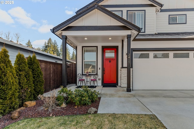 view of exterior entry with covered porch, concrete driveway, board and batten siding, fence, and a garage