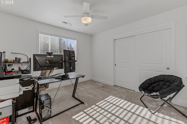 office space featuring light colored carpet, visible vents, ceiling fan, and baseboards