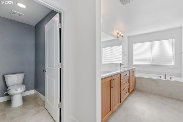 bathroom with a garden tub, double vanity, visible vents, toilet, and a sink