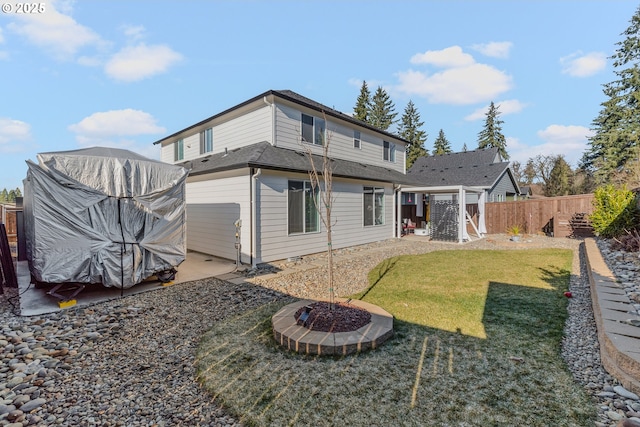 rear view of house with a yard, an outdoor fire pit, a patio, and fence