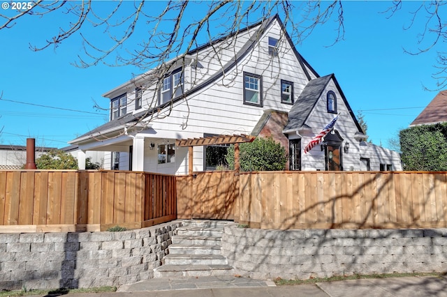 view of front of house featuring fence and a pergola