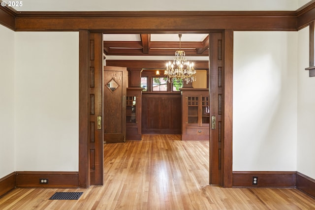 entrance foyer featuring an inviting chandelier, visible vents, baseboards, and hardwood / wood-style flooring